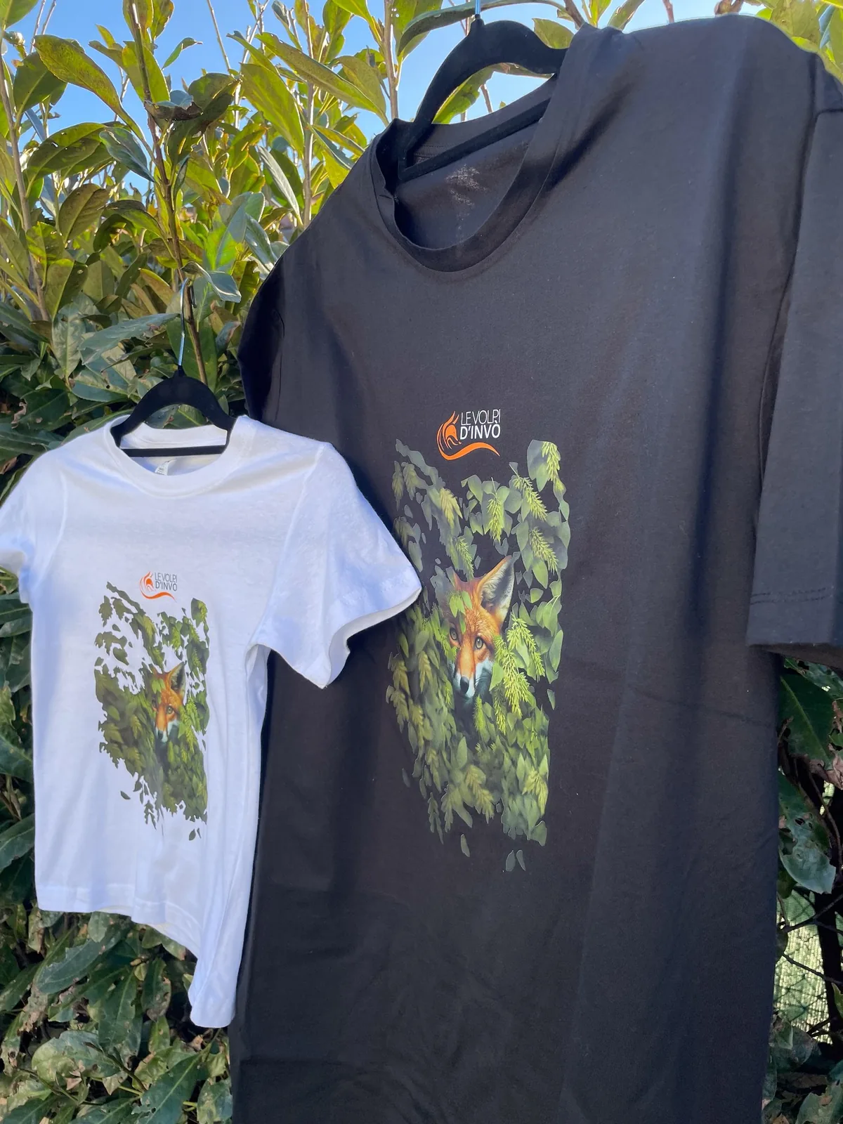 T-shirt bianca e grigia con la volpe stampata, fotografate in giardino
