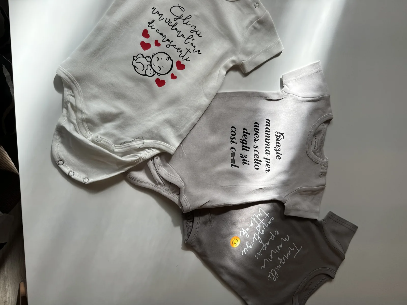 Body da neonato bianchi e grigi con frasi stampate in corsivo
