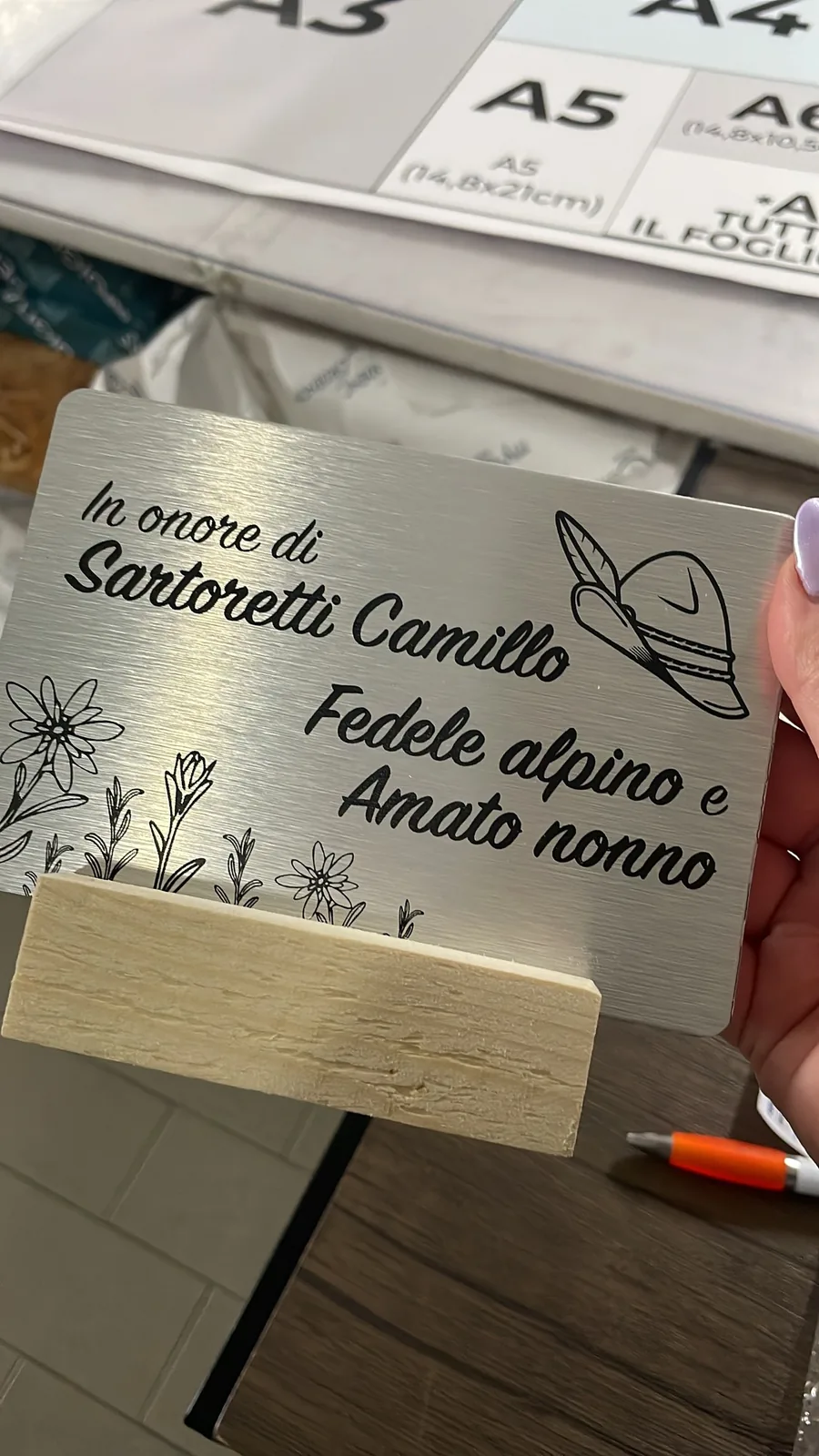 Targa in alluminio incisa «In onore di Sartoretti Camillo, fedele alpino e amato nonno» con cappello e stelle alpine