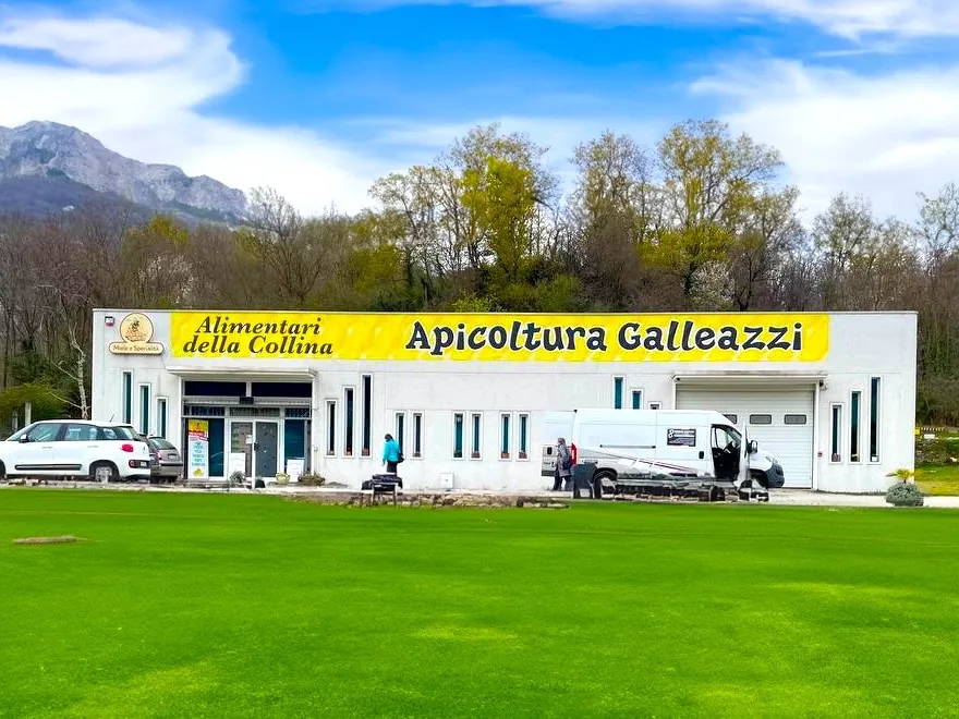 Capannone Apicoltura Galleazzi con la grande insegna gialla, con le montagne sullo sfondo