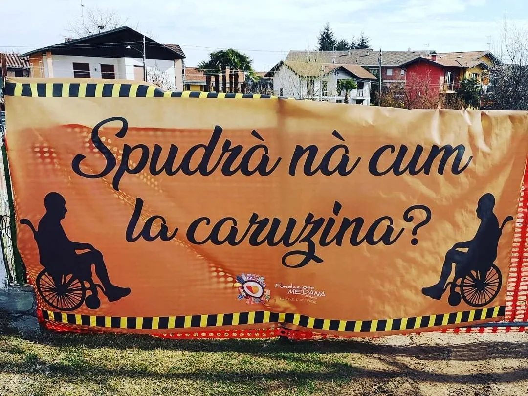 Striscione «Spudrà nà cum la caruzina?» appeso a una recinzione da cantiere