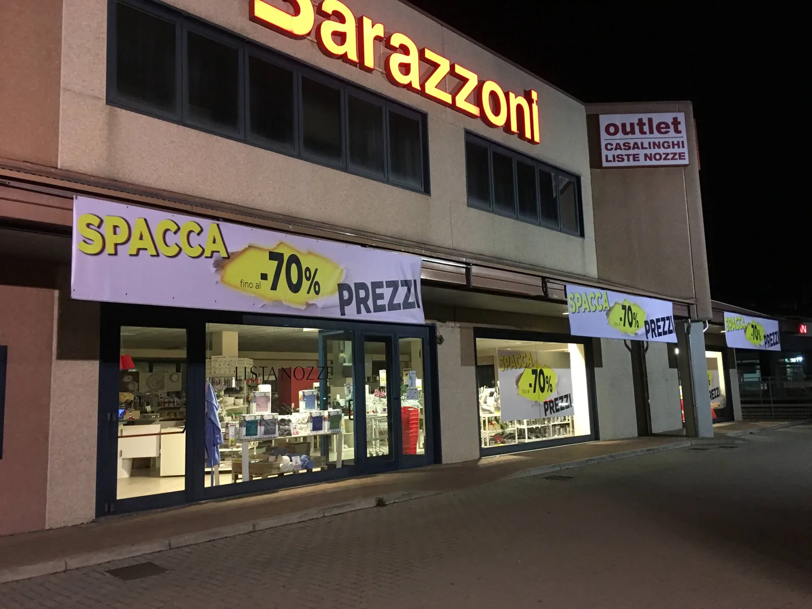Facciata Barazzoni outlet di notte con i banner Spacca prezzi su tutte le vetrine