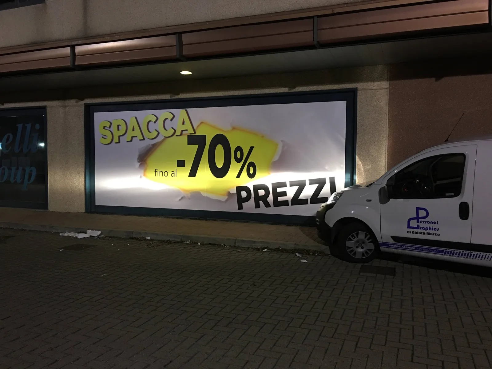 Vetrina Barazzoni di notte con il banner retroilluminato Spacca prezzi -70%