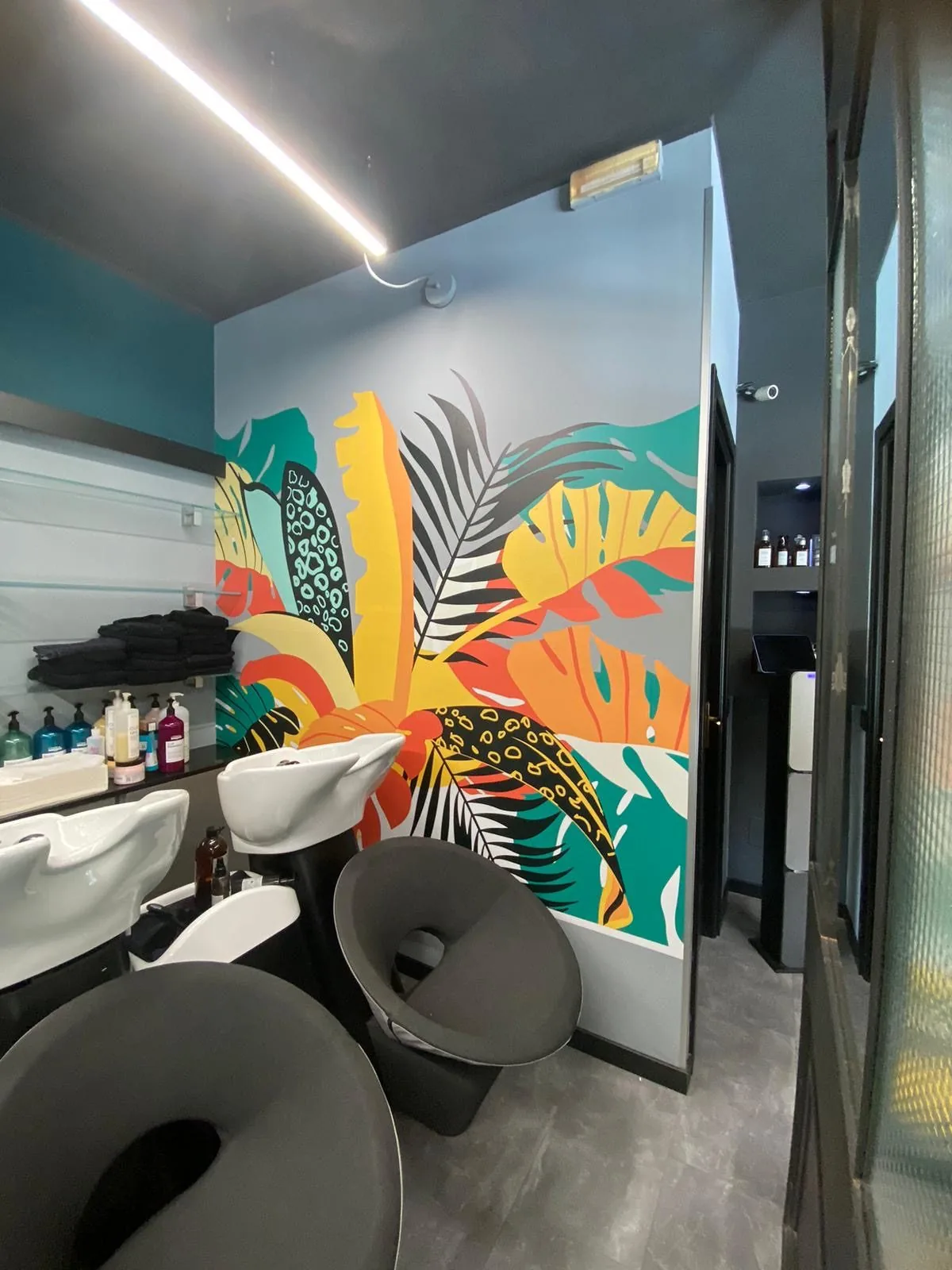 Salone da parrucchiere con una parete rivestita da una grafica tropicale coloratissima