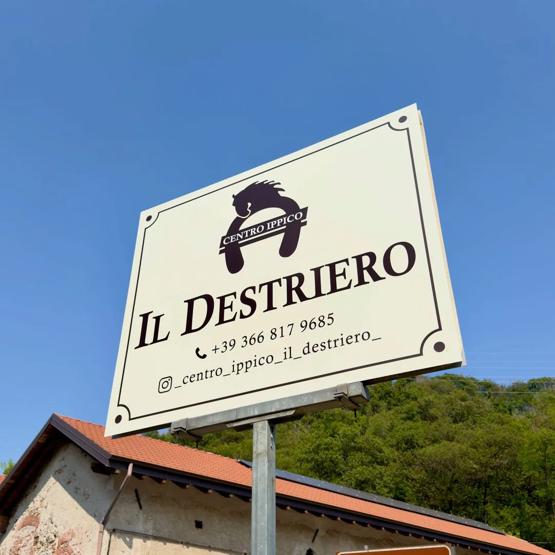 Insegna del centro ippico Il Destriero su palo, contro il cielo azzurro