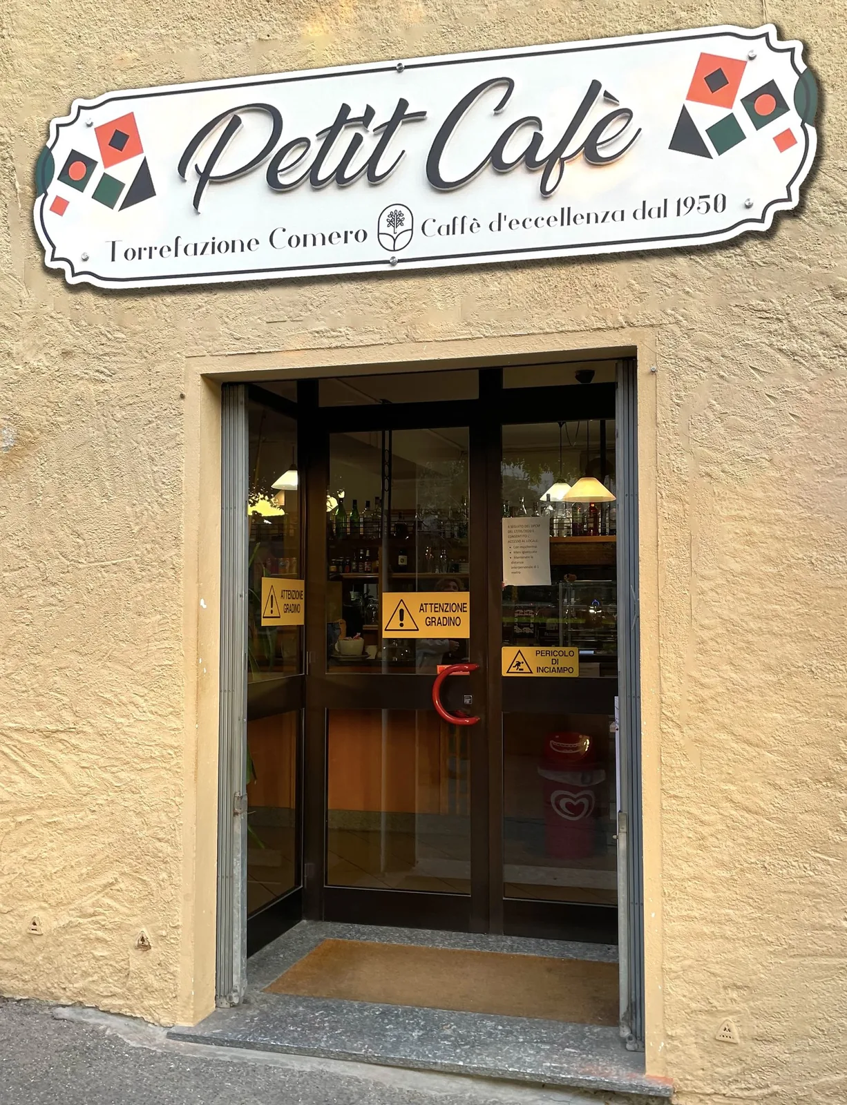 Insegna sagomata Petit Café della Torrefazione Comero sopra l’ingresso del bar