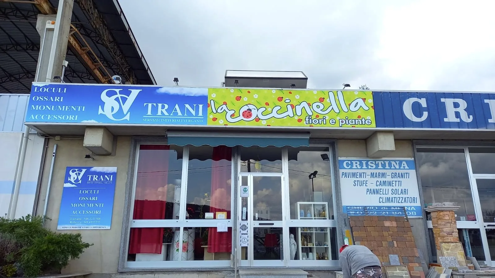 Fila di negozi con le insegne Trani, La Coccinella fiori e piante e Cristina