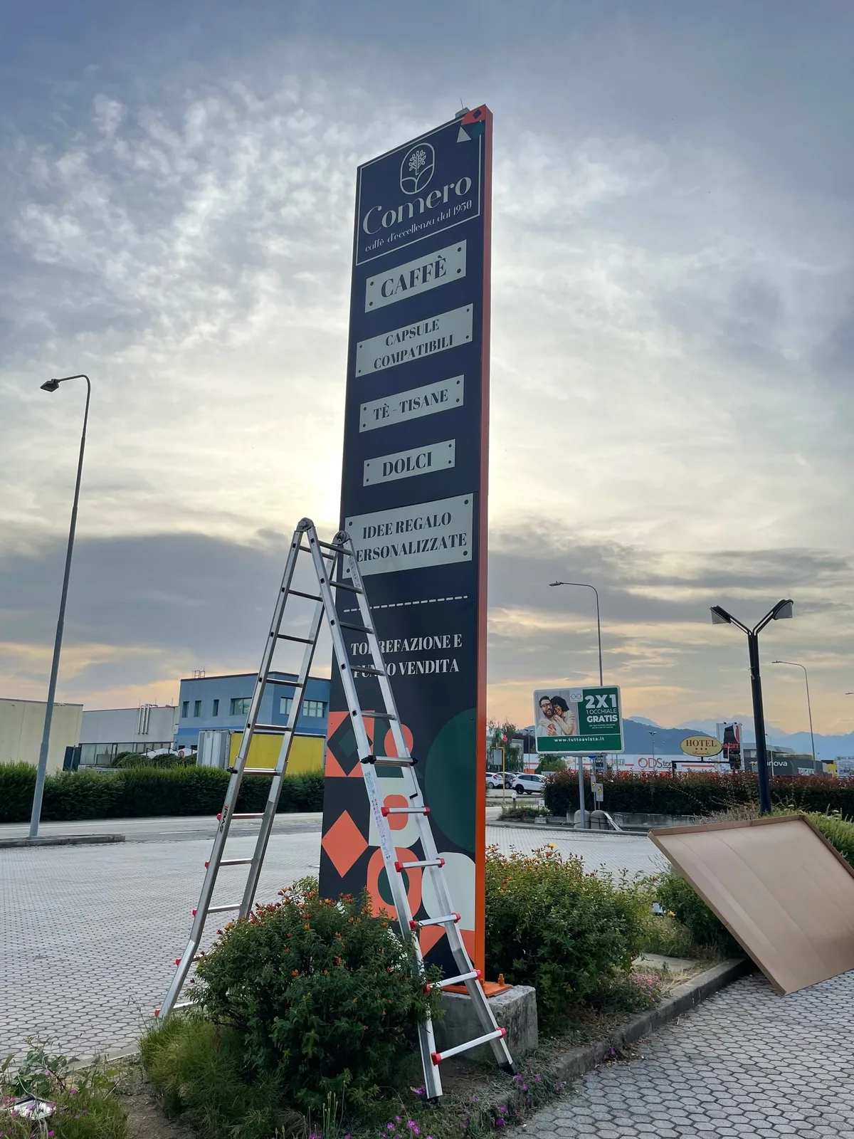 Totem alto Comero con l’elenco dei prodotti, appena montato, al tramonto