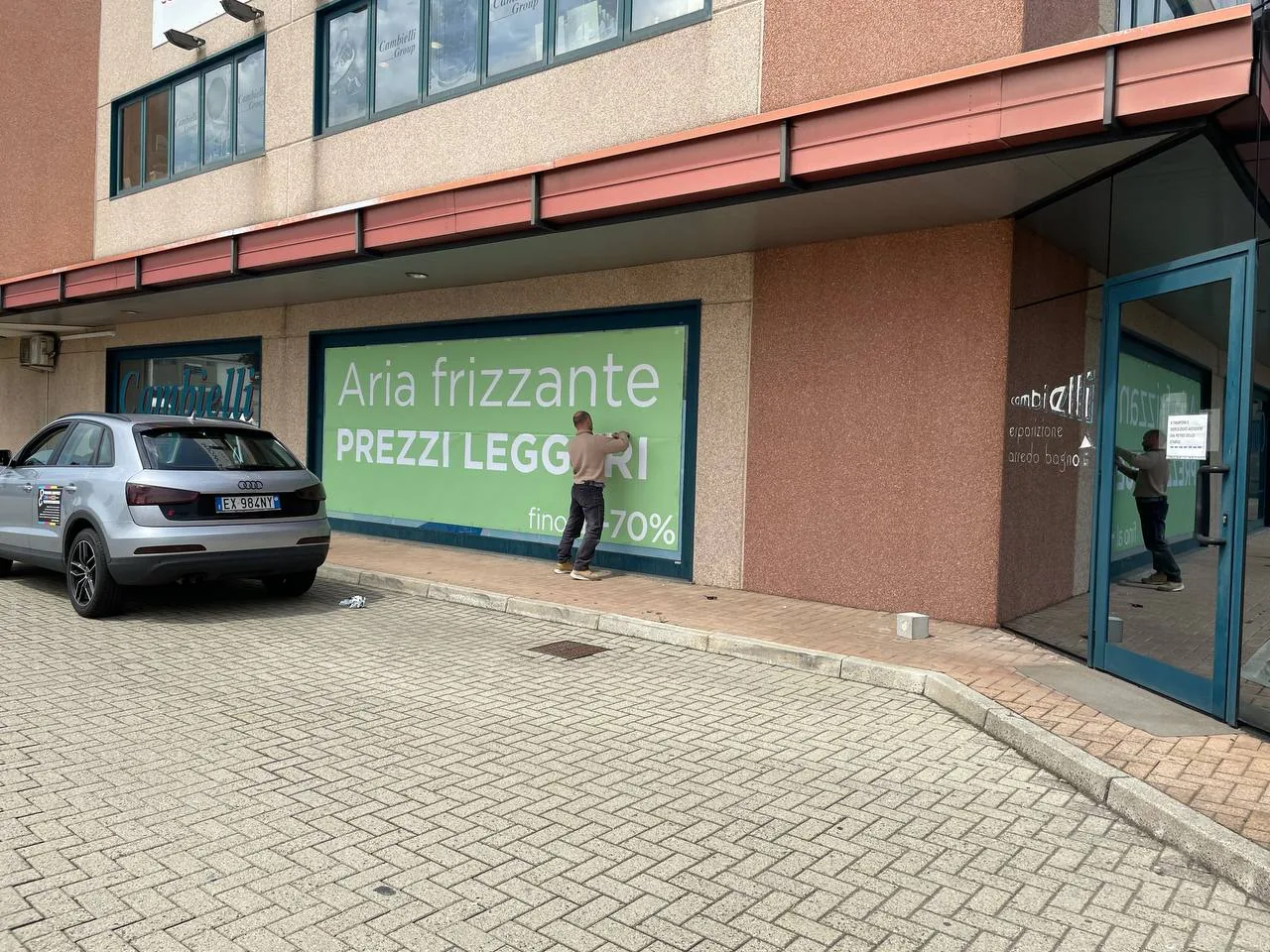 Vetrina decorata con la grafica «Aria frizzante, prezzi leggeri» su tutta la superficie