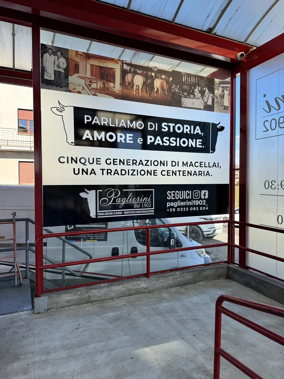 Vetrina della macelleria Paglierini 1902 con la grafica «Parliamo di storia, amore e passione» e l’orario sul vetro