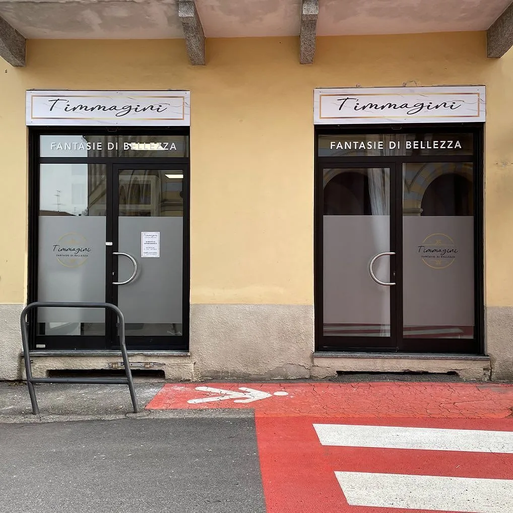 Due ingressi del negozio T’immagini con insegne e scritte «Fantasie di bellezza» sui vetri