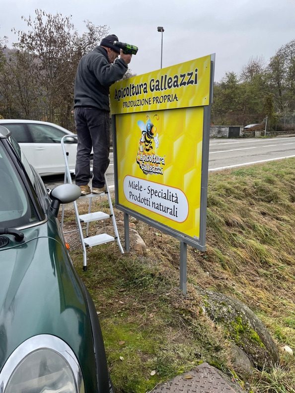 Posa di un cartello Apicoltura Galleazzi a bordo strada